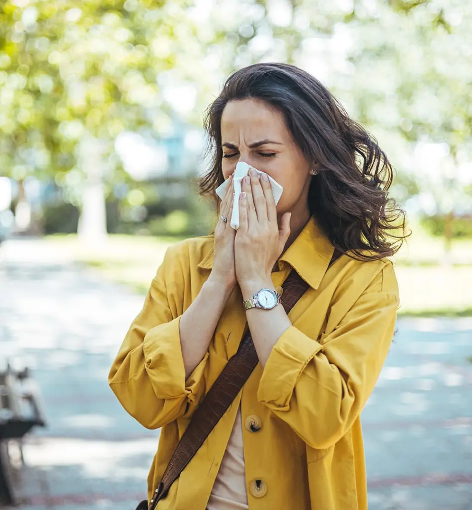 Eine Frau putzt ihre Nase. Sie ist unterwegs.