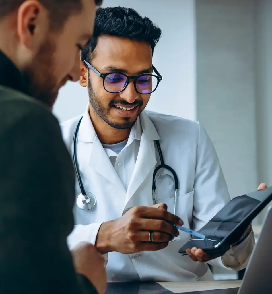 Ein Arzt zeigt einem Mann auf einem Tablet etwas. Das Bild wird im Bereich "Ambulante Operation" verwendet.