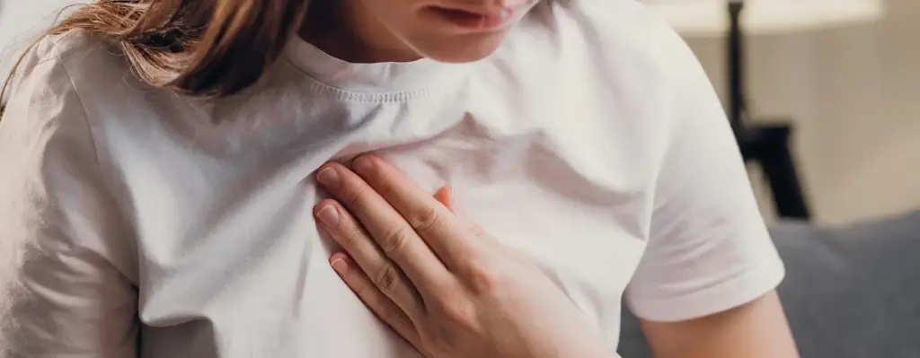Eine Frau fasst sich mit ihrer Hand ans Herz. Das Bild wird im Bereich "Ambulante Versorgung bei tachykarden Herzrhythmusstörungen durch Kardioversion" verwendet.