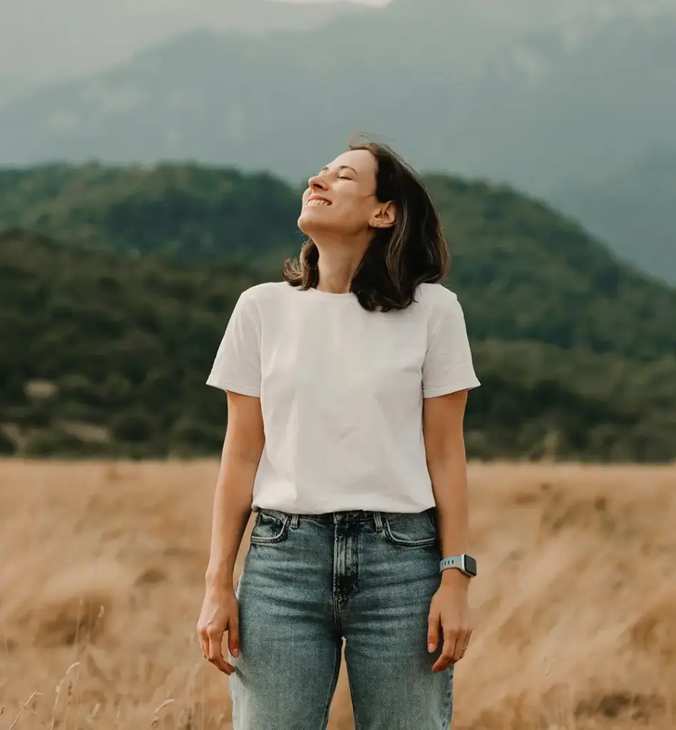 Eine Frau steht auf einem Feld und blickt mit geschlossenen Augen und gehobenen Kopf Richtung Himmel. Das Bild wird im Bereich "Arzneimittel Homöopathie, Phytotherapie und Anthroposophie" verwendet.