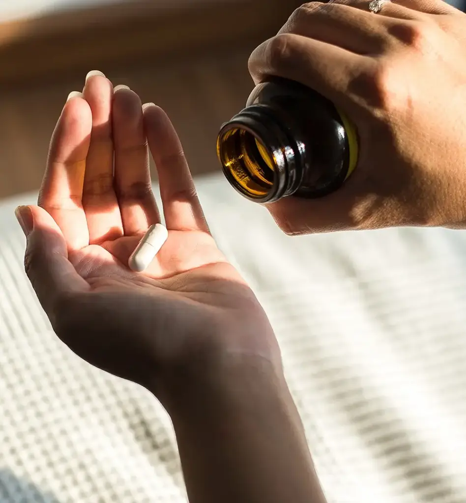 Eine Frau lässt sich aus einem Gläschen eine Tablette in die Hand fallen. Das Bild wird im Bereich "Arzneimittel" verwendet.