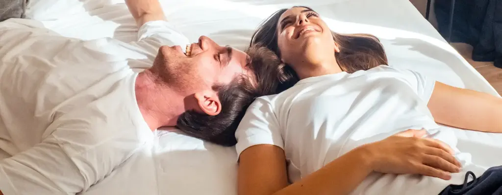 Ein Paar liegt auf einem Bett. Das Bild wird im Bereich "Empfängnisregelung und Empfängnisverhütung" verwendet.