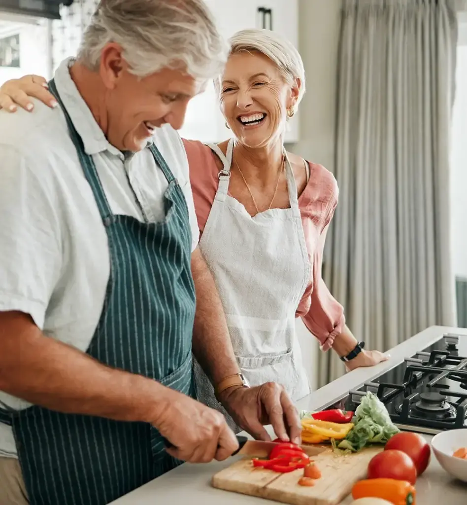 Ein älteres Pärchen steht in der Küche und kocht. Sie lachen. Das Bild wird im Bereich "Ernährungsberatung" verwendet.
