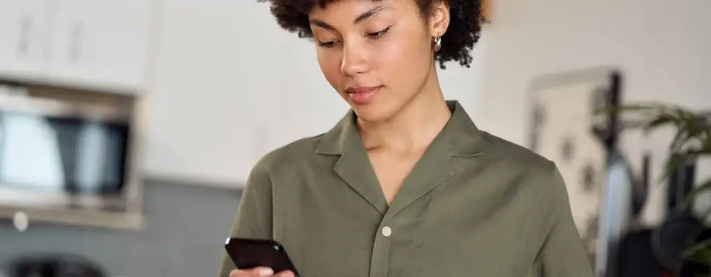Eine Frau hält ein Glas in der einen und ein Smartphone in der anderen Hand. Das Bild wird im Bereich "Fimo Health App – Alltagsbegleiter bei Long Covid" verwendet.