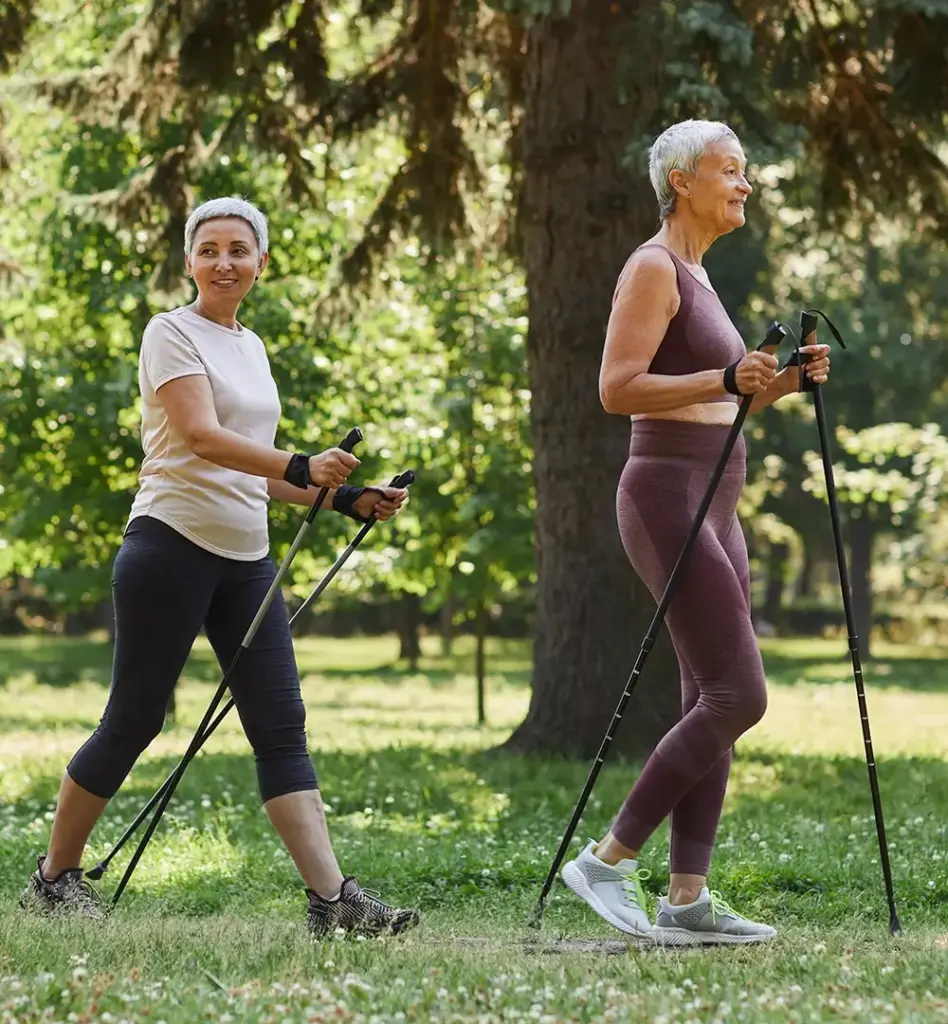 Zwei ältere Damen in Sportkleidung walken durch einen Park. Das Bild wird im Bereich "fit for well Tage" verwendet.