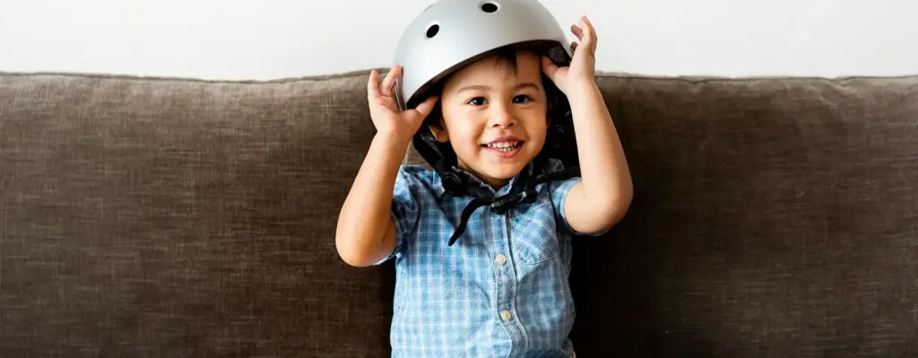 Ein kleiner Junge sitzt mit Helm auf einer Couch. Das Bild wird im Bereich "Helmtherapie" verwendet.