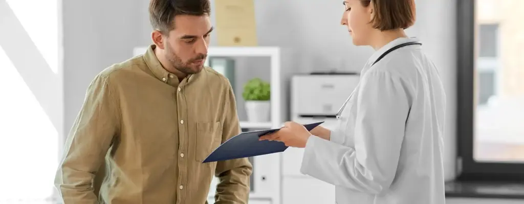 Das Bild zeigt eine Ärztin im weißen Kittel, die einem männlichen Patienten mittleren Alters etwas auf einem Dokument zeigt. Das Bild wird im Bereich "Mpmrt bei Prostatakarzinom" verwendet.