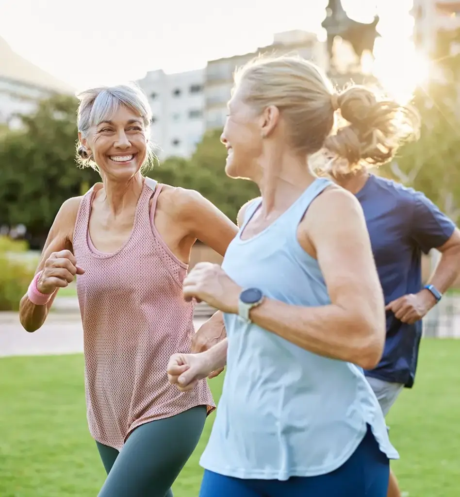 Eine Gruppe von 4 Personen mittleren Alters joggen gemeinsam. Zwei Frauen laufen vorab, zwei Männer folge. Die beiden Frauen blicken sich an. Das Bild wird im Bereich "ProHerz" und "Präventionskurse" verwendet.