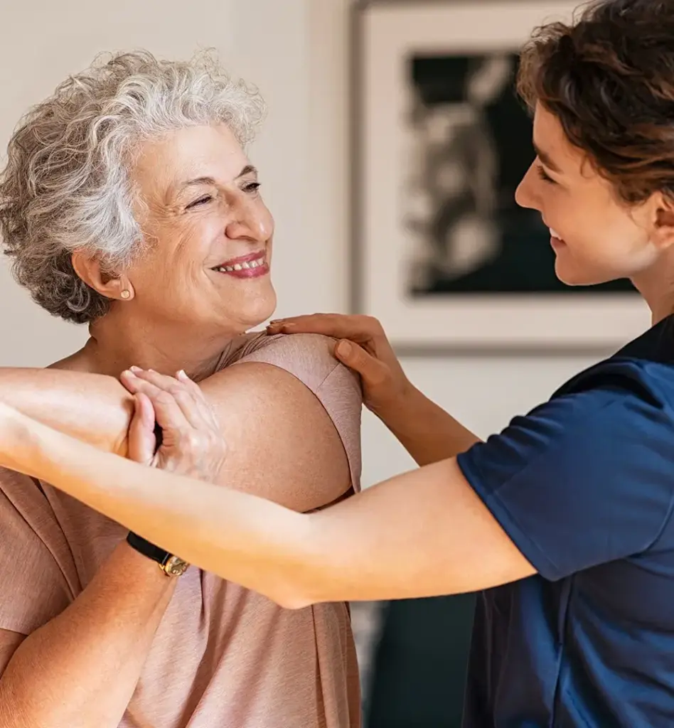 Eine ältere Frau dehnt ihren Arm. Eine jüngere Frau unterstützt sie dabei. Das Bild wird im Bereich "Rehasport und Funktionstraining" verwendet.