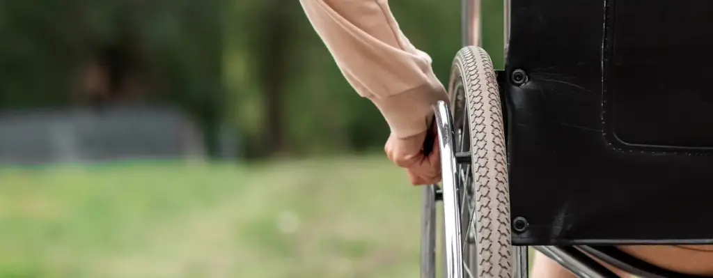 Das Bild zeigt eine Nahaufnahme eines Rollstuhls, an dessen Rad eine Hand zu sehen ist. Das Bild wird im Bereich "Stationäre Vorsorgekur" verwendet.