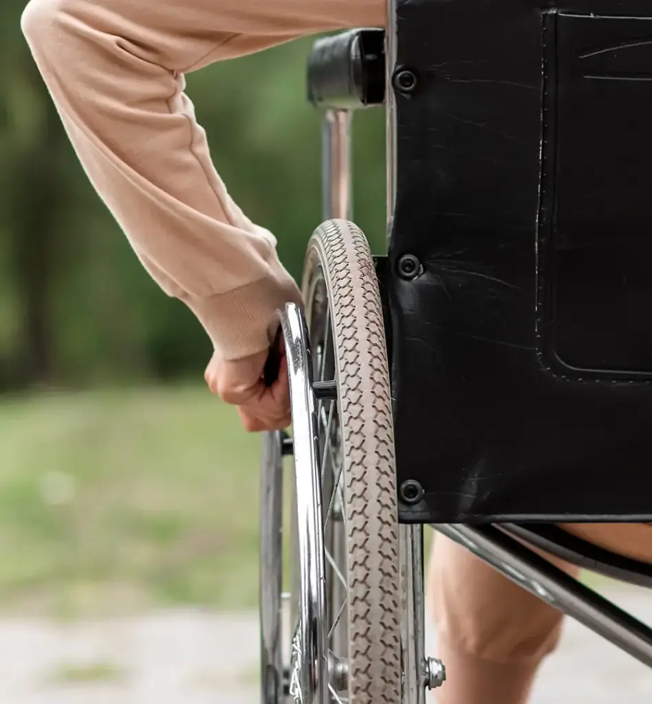 Das Bild zeigt eine Nahaufnahme eines Rollstuhls, an dessen Rad eine Hand zu sehen ist. Das Bild wird im Bereich "Stationäre Vorsorgekur" verwendet.