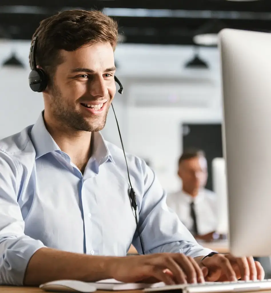 Das Bild zeigt einen jungen Mann mit Hemd, der ein Headset trägt und an einem PC sitzt. Das Bild wird im Bereich "Terminservicestellen" verwendet.