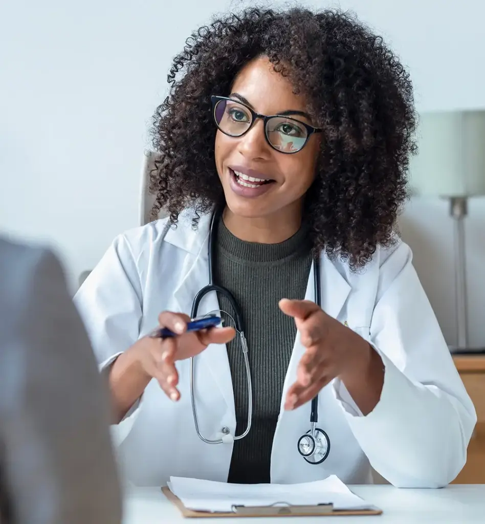 Das Bild zeigte eine Frau mit Brille. Sie ist Ärztin und erklärt ihrer Patientin vor sich etwas. Das Bild wird im Bereich "Versorgungsprogramme" verwendet.