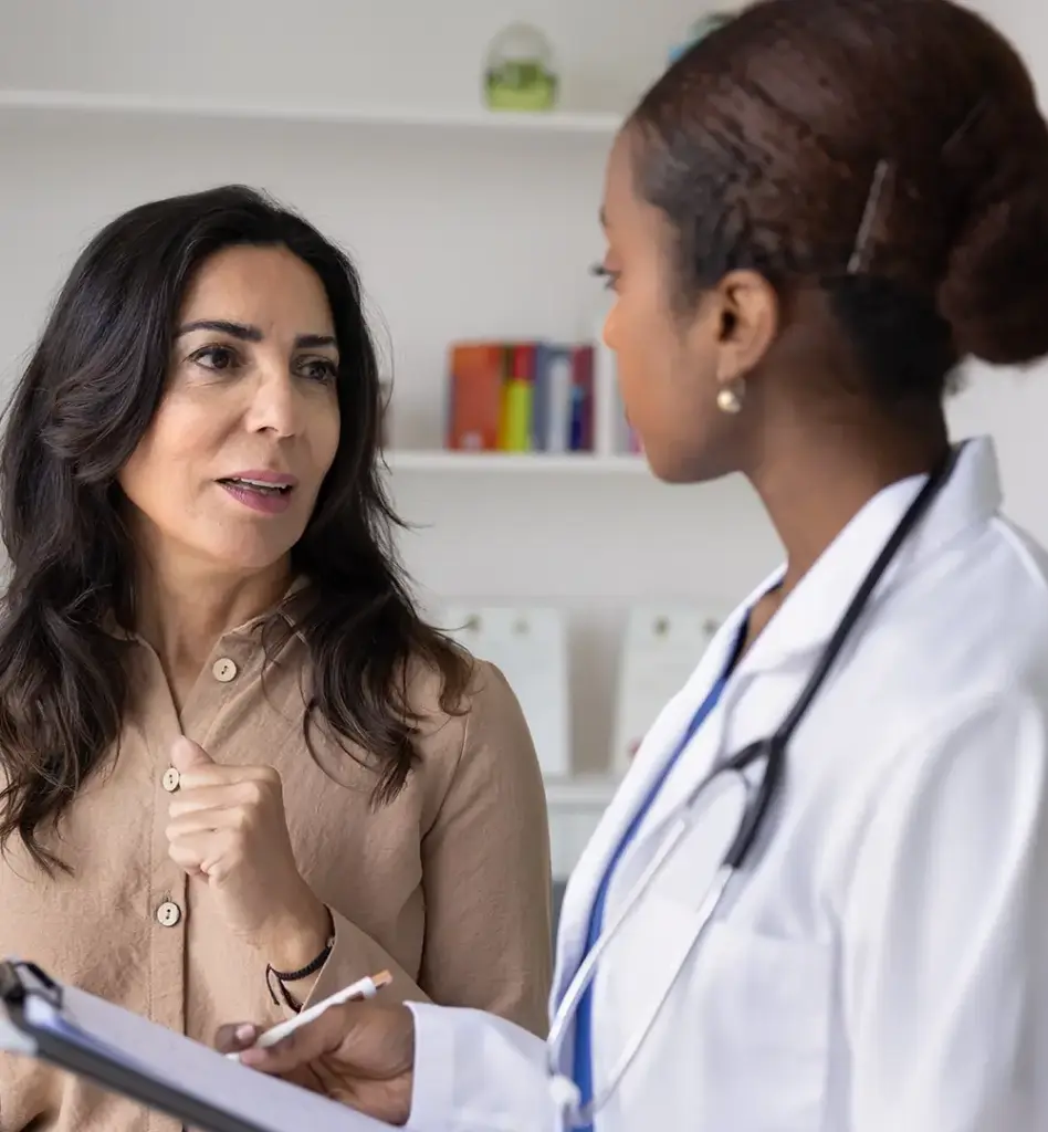 Das Bild zeigt eine Frau, die sich mit einer Ärztin unterhält. Sie stehen in einer Arztpraxis. Das Bild wird im Bereich "Zweitmeinungsservice" verwendet.