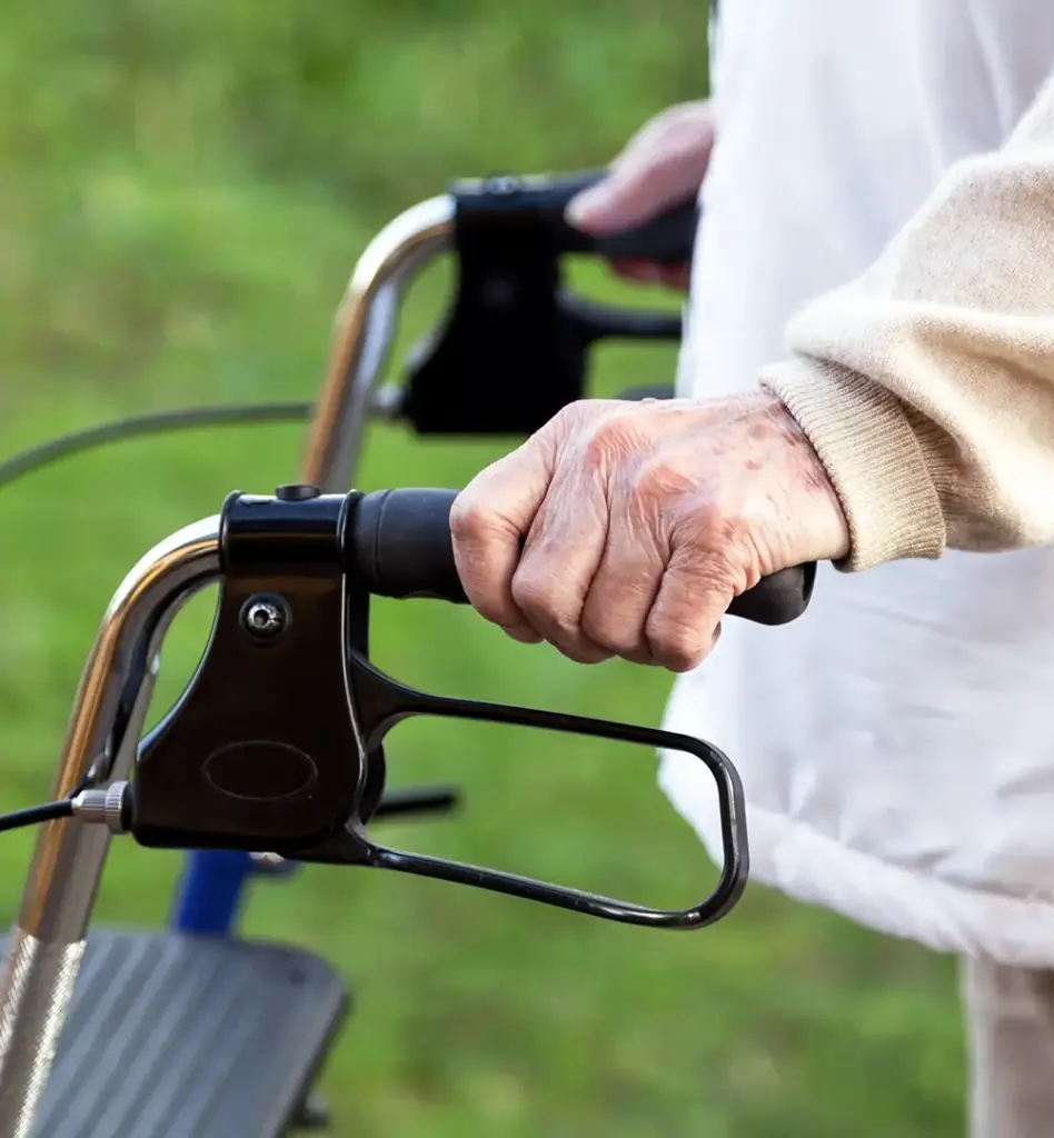 Das Bild zeigt Hände einer älteren Person, die sich an einem Rollator festhält. Das Bild wird im Bereich "Pflegehilfsmittel" verwendet.