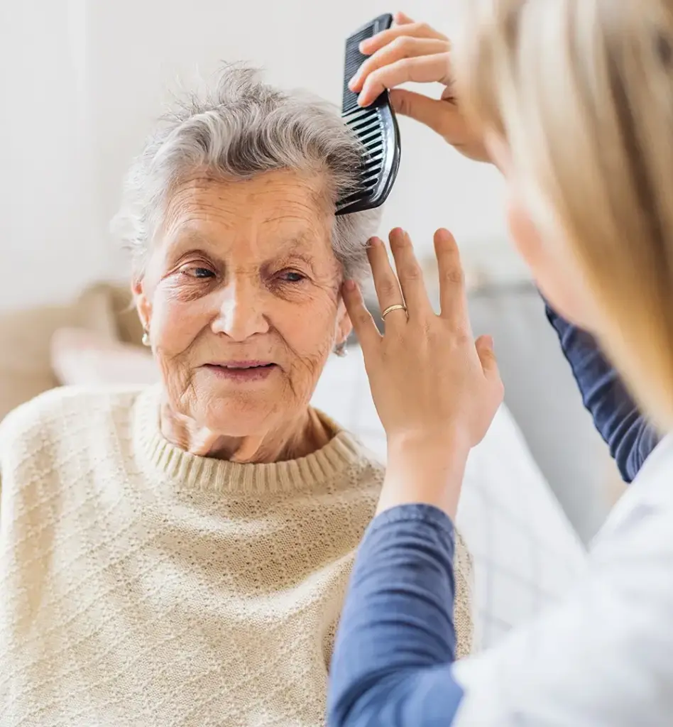 Das Bild zeigt eine ältere Frau, die von einer jüngeren Frau gekämmt wird. Das Bild wird im Bereich "Vollstationäre Pflege" verwendet.