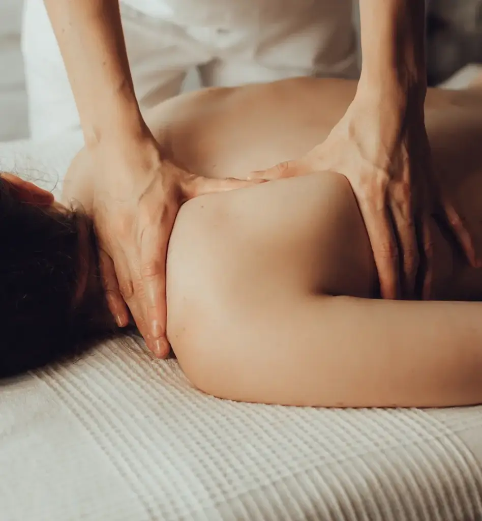 Das Bild zeigt eine Frau auf einer Massageliege. Eine andere Person massiert ihren Rücken. Das Bild wird im Bereich "Als Familie gesund bleiben und Bonus sichern" verwendet.