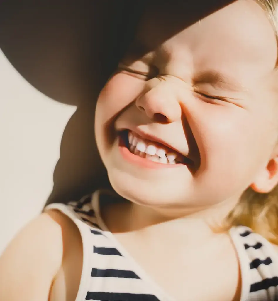 Ein Mädchen strahlt in die Sonne mit geschlossenen Augen. Das Bild wird im Bereich "Fissurenversiegelung" verwendet.
