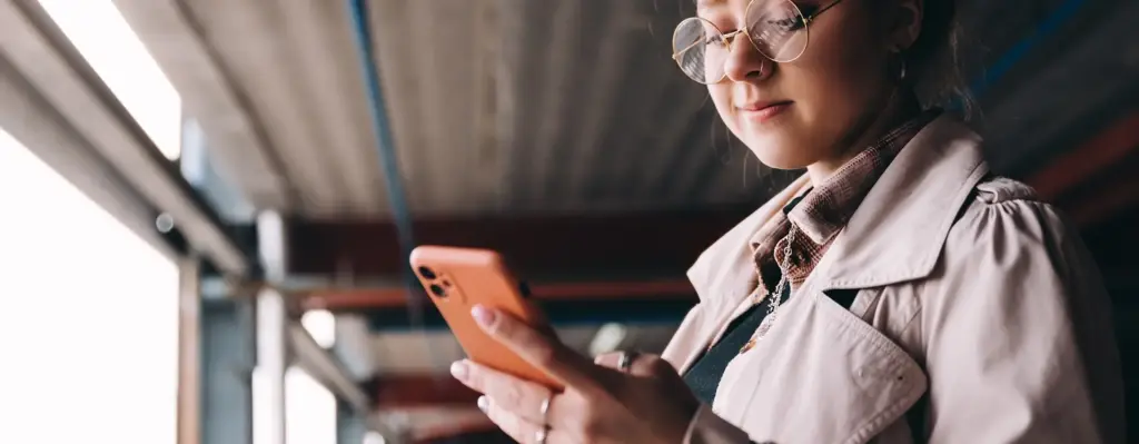 Das Bild zeigt eine jüngere Frau mit Brille und Nasenpiercing. Sie hält ein Smartphone in der Hand und blickt darauf. Das Bild wird im Bereich "Medizinischer Rat – wann und wo du ihn brauchst" verwendet.