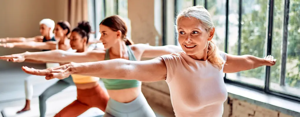 Eine Gruppe von Frauen macht Sport in einem Studio gemeinsam. Eine Frau im Vordergrund ist mittleren Alters. Das Bild wird im Bereich "ProHerz" und "Präventionskurse" verwendet.