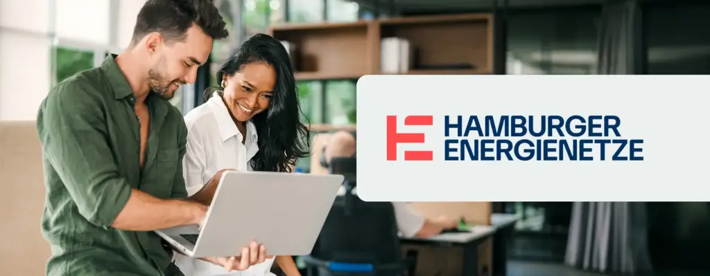 Das Bild zeigt eine Arbeitssituation zwischen einem Mann und einer Frau, die gemeinsam auf einen Laptop gucken. Rechts ist das Logo von Hamburger Energienetze zu sehen.