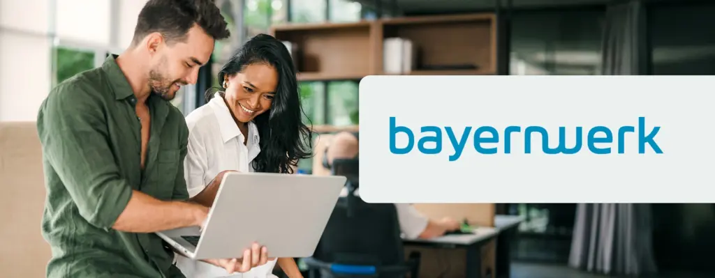 Das Bild zeigt eine Arbeitssituation zwischen einem Mann und einer Frau, die gemeinsam auf einen Laptop gucken. Rechts ist das Logo von bayernwerk zu sehen.