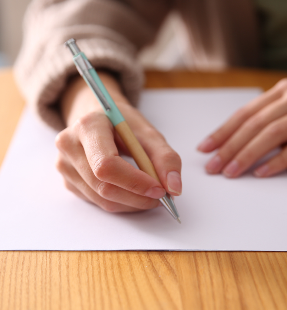 Zu sehen ist ein Blatt Papier und eine Hand die einen Stift hält