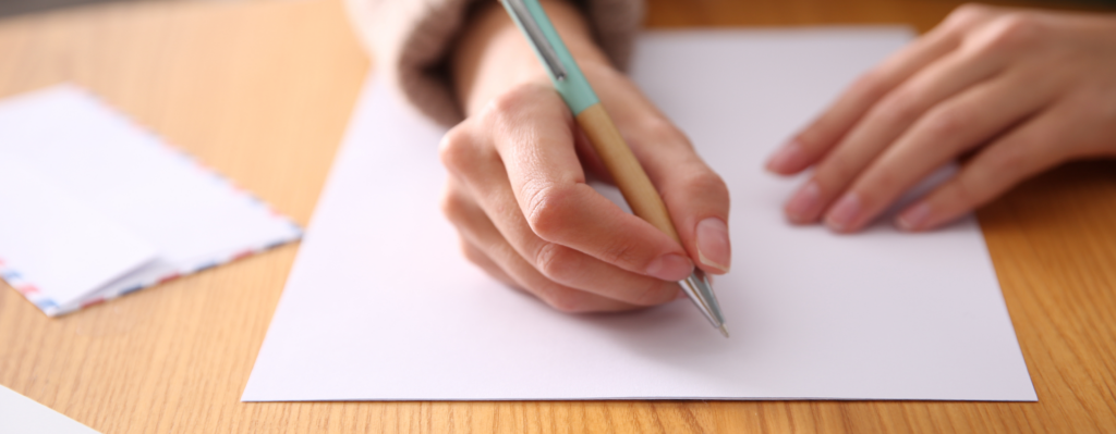 Zu sehen ist ein Blatt Papier und eine Hand die einen Stift hält