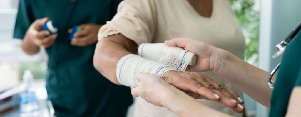 Das Bild zeigt wie ein Wundverband an der Hand angelegt wird