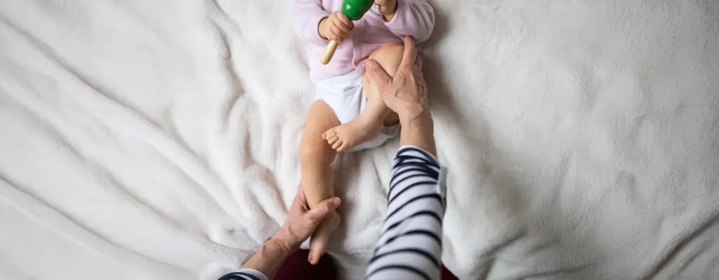 Eine Osteopathin macht mit einem Baby Bewegungsübungen für die Beine