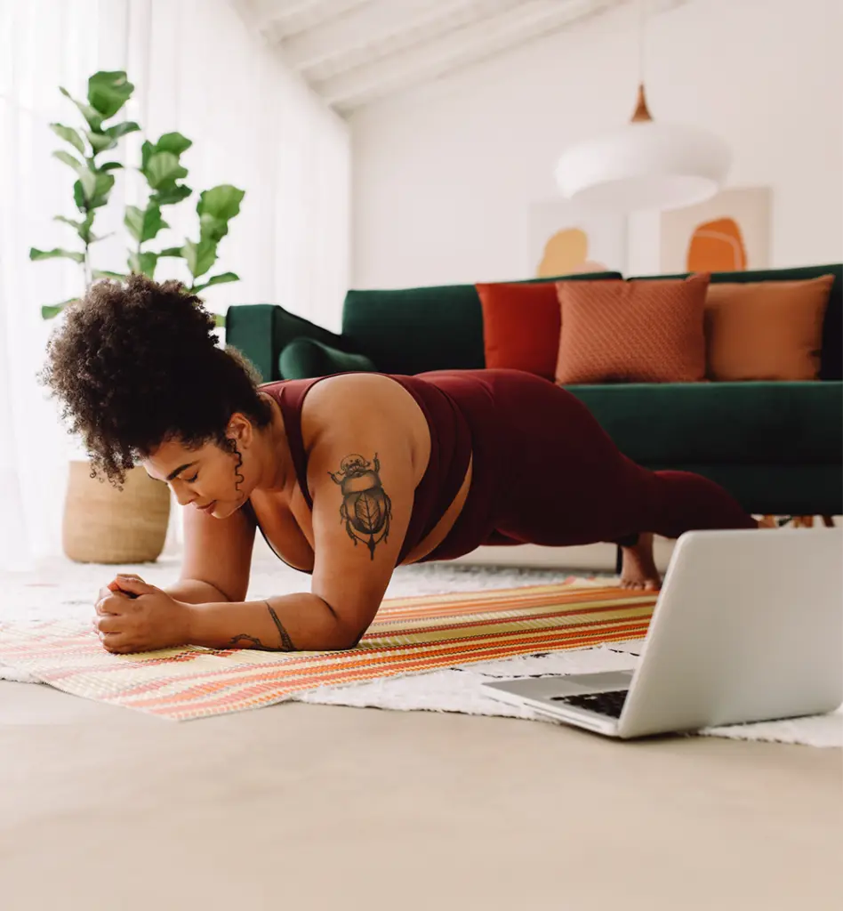 Eine Frau of color macht in einem Gymnastikoutfit eine Plank-Übung