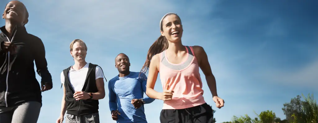 Eine Gruppe junger Leute joggt im Sommer durch einen Park