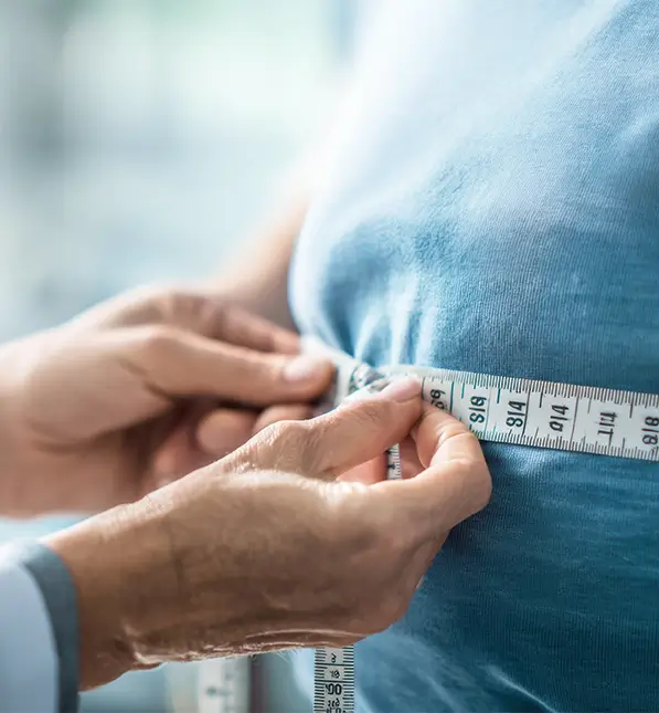 Auf dem Bild vermisst ein Arzt den Bauchumfang seines Patienten mit einem Zentimetermaßband