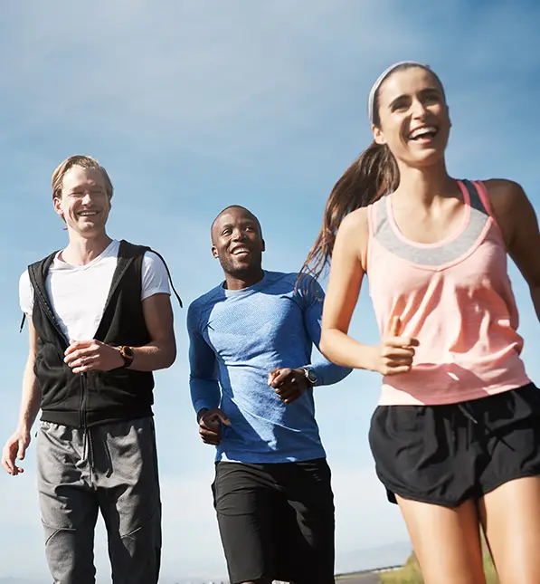 Eine Gruppe junger Leute joggt im Sommer durch einen Park