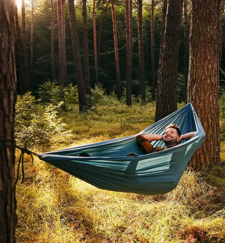 Mann entspannt in einer blauen Hängematte zwischen Kiefern im Wald – Waldbaden und Erholung in der Natur, warmes Sonnenlicht.