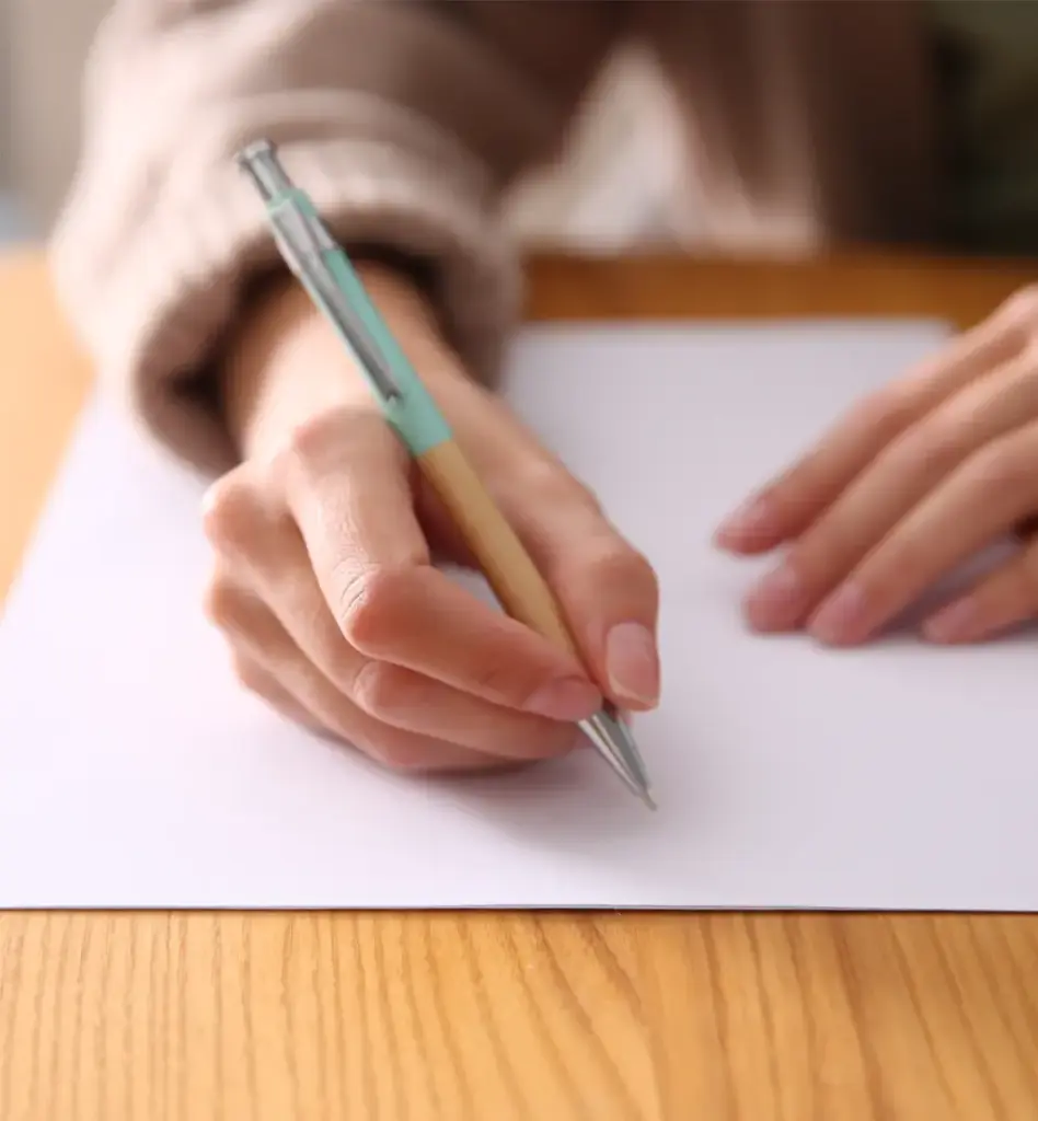 Zu sehen ist ein Blatt Papier und eine Hand die einen Stift hält