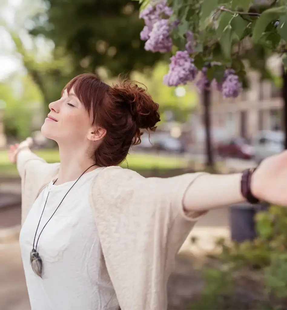Eine Frau holt tief Luft mit ausgebreiteten Armen