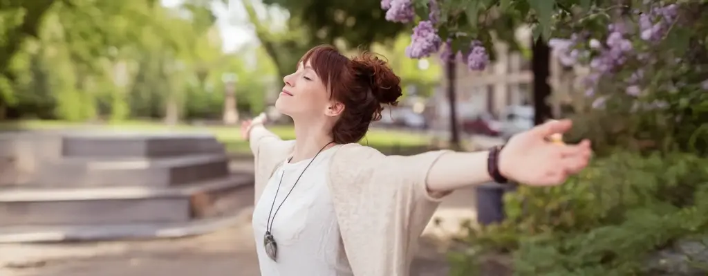 Eine Frau holt tief Luft mit ausgebreiteten Armen